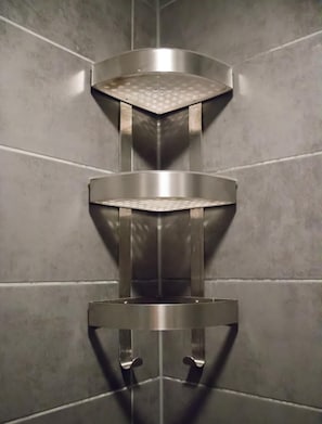 A corner shower with a stainless steel design, featuring a central drain and two side handles. - Crossroads Hostel Amsterdam (Amsterdam)