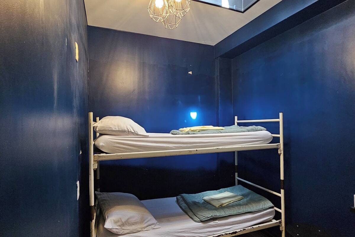 A bunk room with a skylight, a ceiling fan, and a radiator.