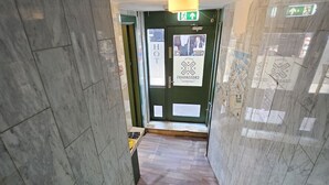 A staircase with a wooden floor, a handrail, and a green door with a sign. - Crossroads Hostel Amsterdam (Amsterdam)