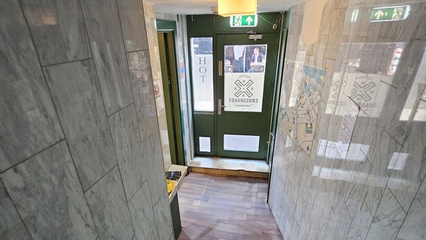 Una escalera con piso de madera, barandilla y una puerta verde con un cartel.