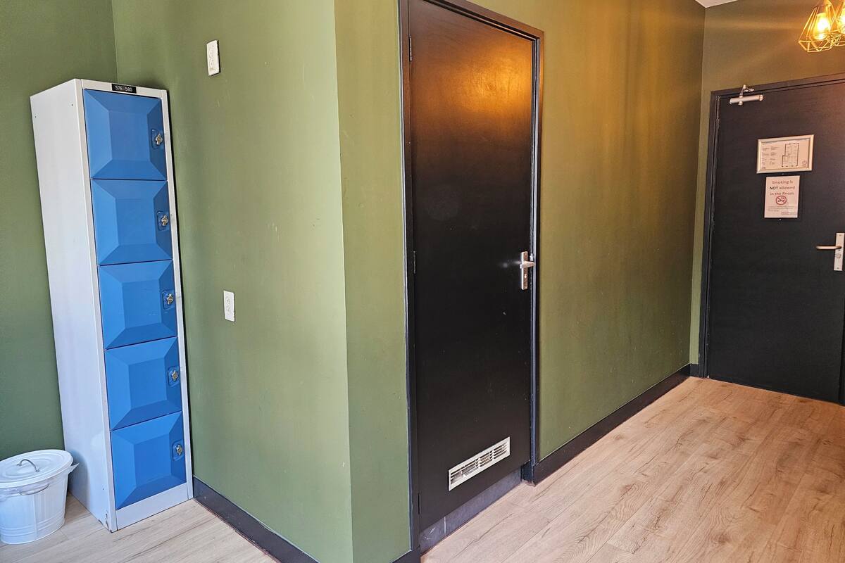 A hallway with a blue storage unit, a black door, and a wooden floor.