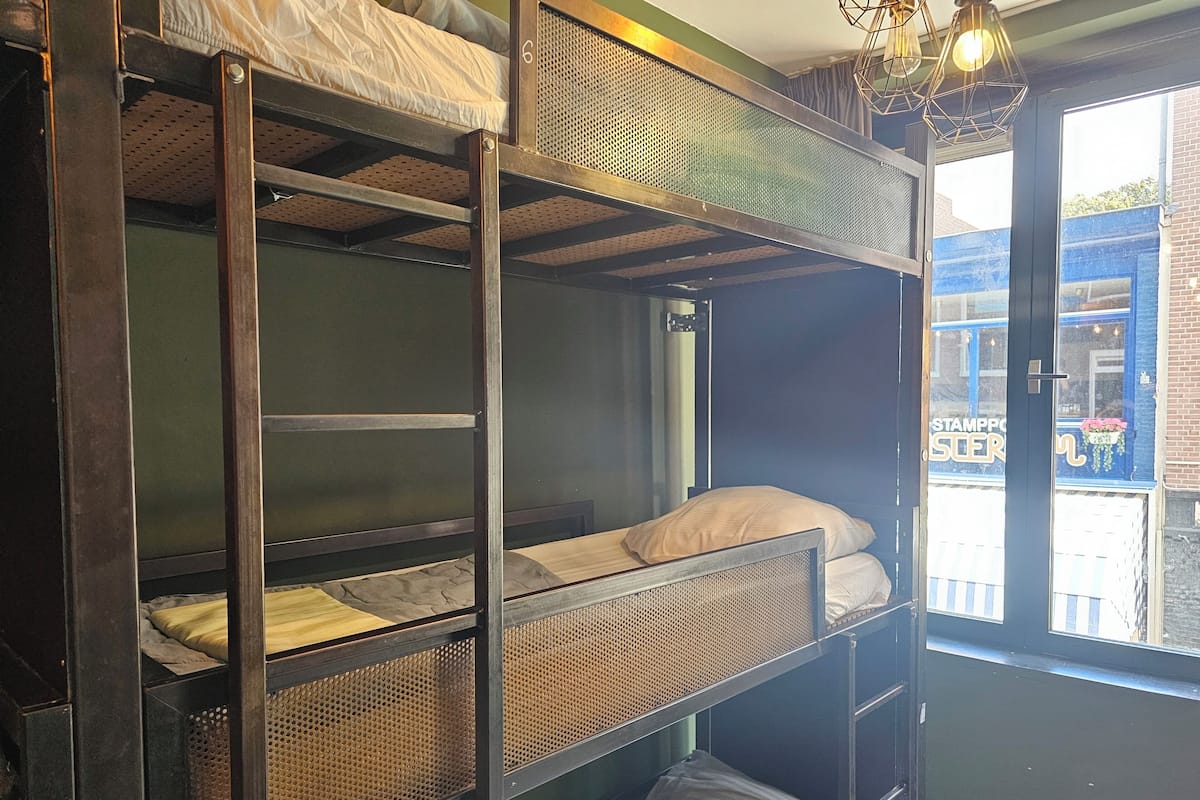 A bunk bed with a window view, a door, and a hanging light fixture.