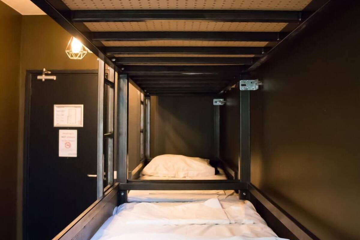 A narrow hallway with bunk beds, a door with a sign, and a light fixture.