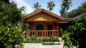 A wooden bungalow with a balcony, surrounded by lush greenery and palm trees. - The Fisherman's Chalet (Koh Samui)