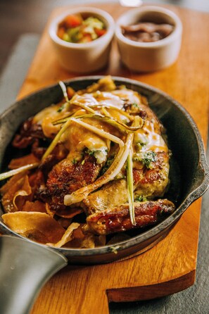 A skillet with a dish of chicken and vegetables, accompanied by two small bowls of condiments.