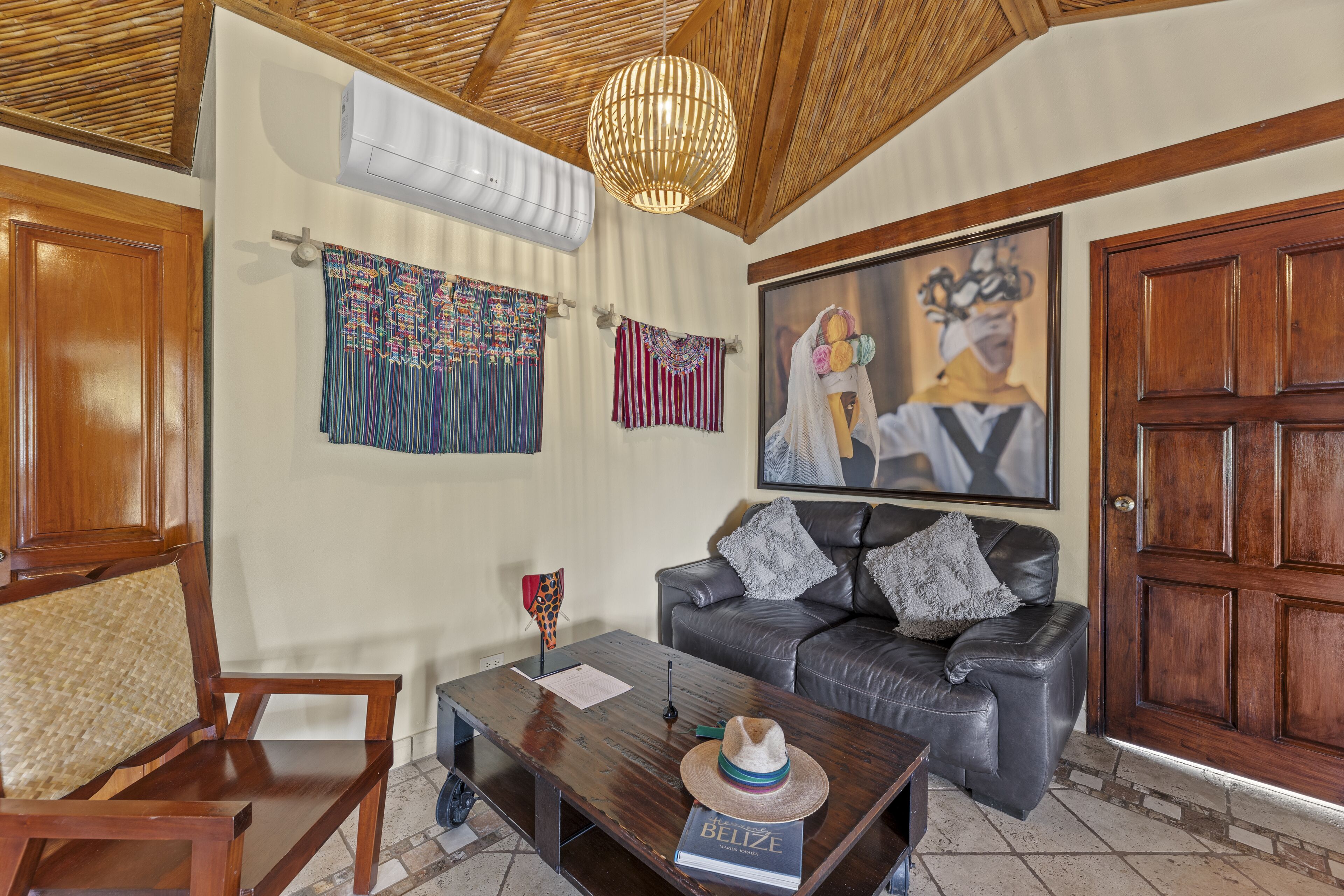 A living room with a wooden ceiling, a leather sofa, a coffee table, and a painting on the wall.
