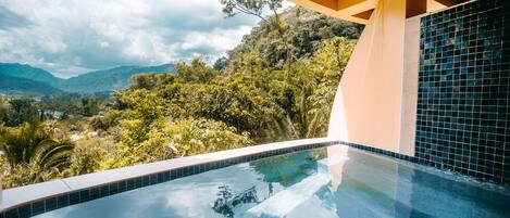 A modern infinity pool with a clear view of lush greenery and mountains in the background.
