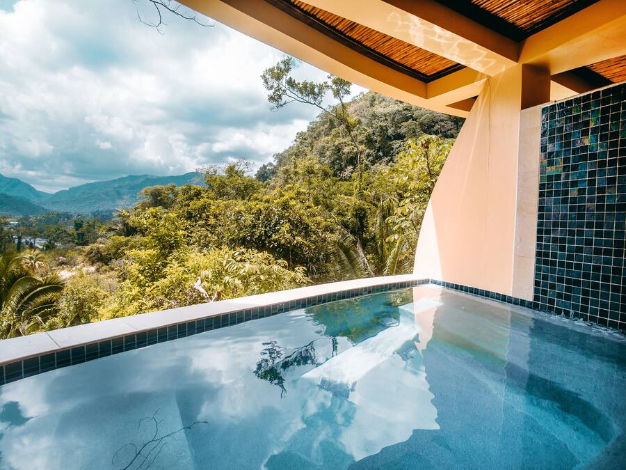 A modern infinity pool with a clear view of lush greenery and mountains in the background.