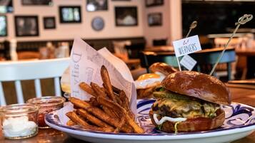 A plate with a burger and fries, a small glass container, and a menu.
