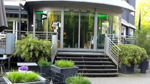 A modern building with a sign reading "VESSINGER" at the entrance. There are outdoor seating areas with chairs and planters. - Hotel Restaurant Wessinger (Neu-Isenburg)