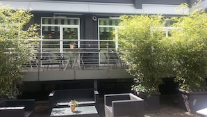A building with a balcony, outdoor seating, and potted plants. - Hotel Restaurant Wessinger (Neu-Isenburg)