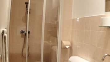 A bathroom with a glass shower enclosure, a toilet, and a sink.