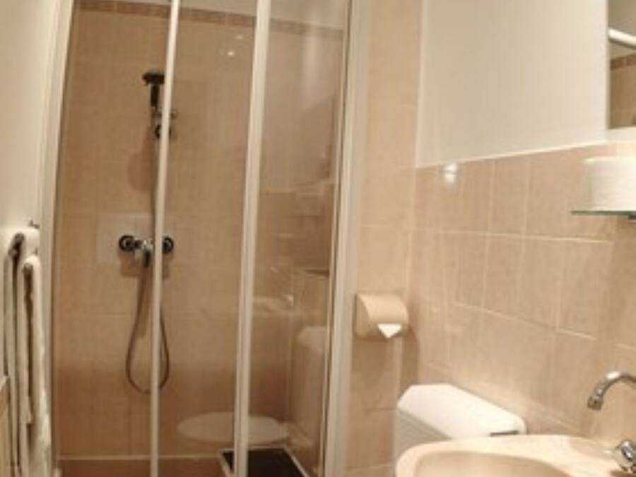A bathroom with a glass shower enclosure, a toilet, and a sink.