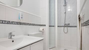 A bathroom with a white sink, toilet, and shower.
