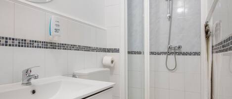 Un baño con lavamanos, inodoro y ducha blancos.