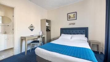 A hotel room with a large bed, a desk, a chair, a wardrobe, and a picture on the wall.