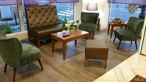 A cozy seating area with a brown sofa, a wooden coffee table, and patterned chairs. - Royal Hôtel (Versailles)
