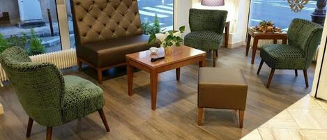 A cozy seating area with a brown sofa, a wooden coffee table, and patterned chairs.