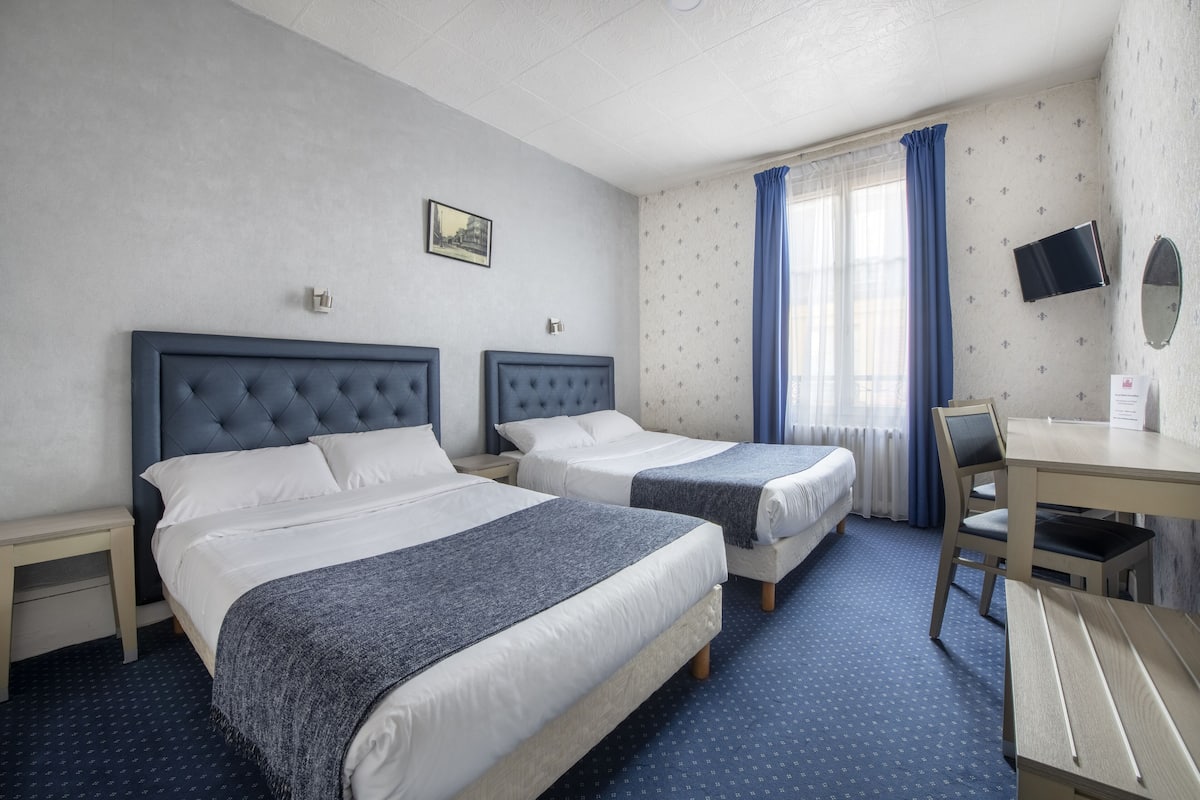 A hotel room with two beds, a desk, and a chair.