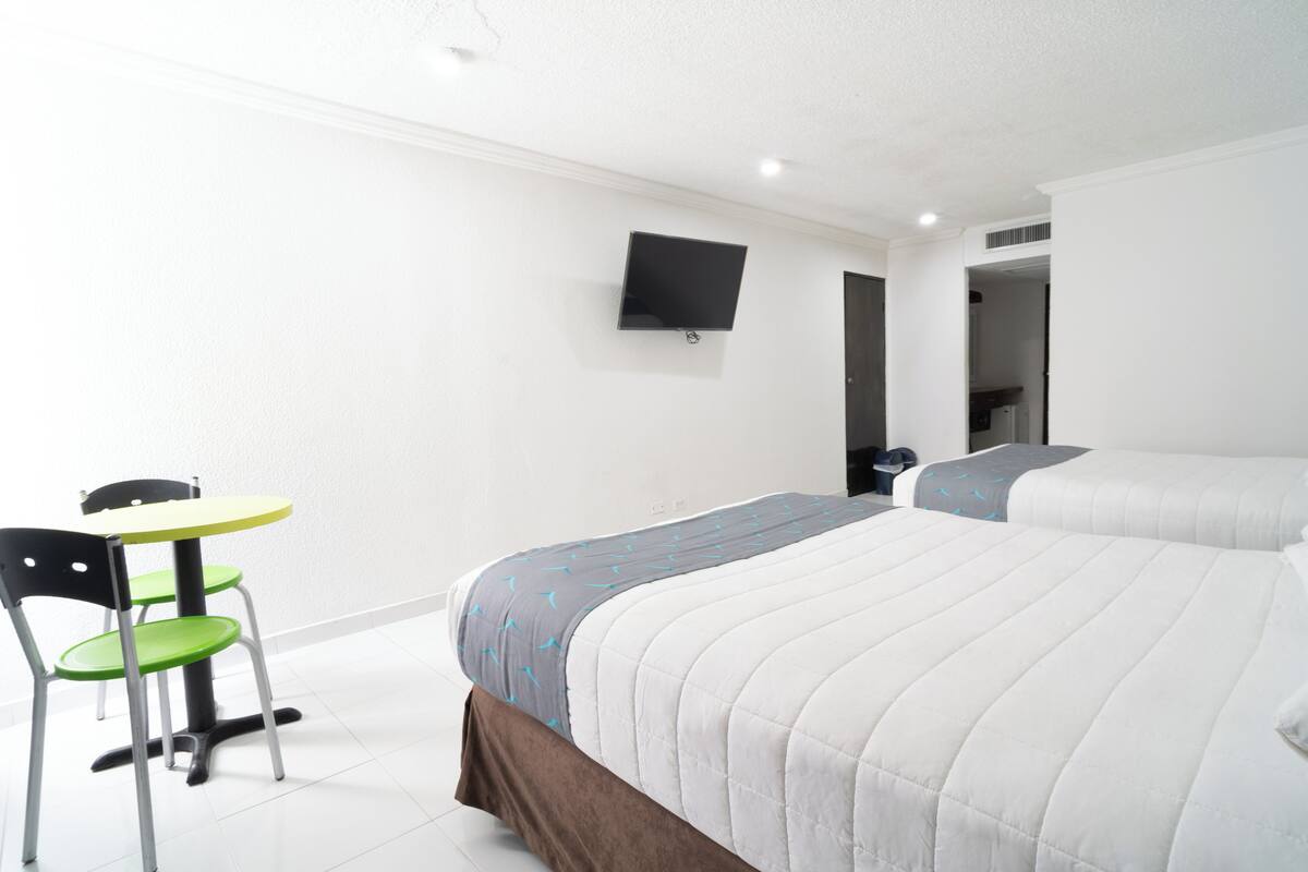 A hotel room with a bed, a desk, a chair, and a TV mounted on the wall.
