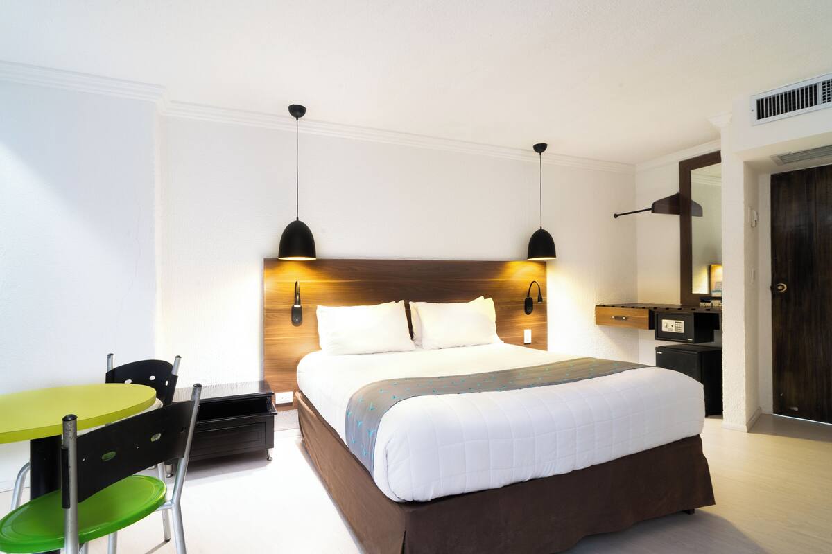 A hotel room with a bed, a desk, a chair, and a table.
