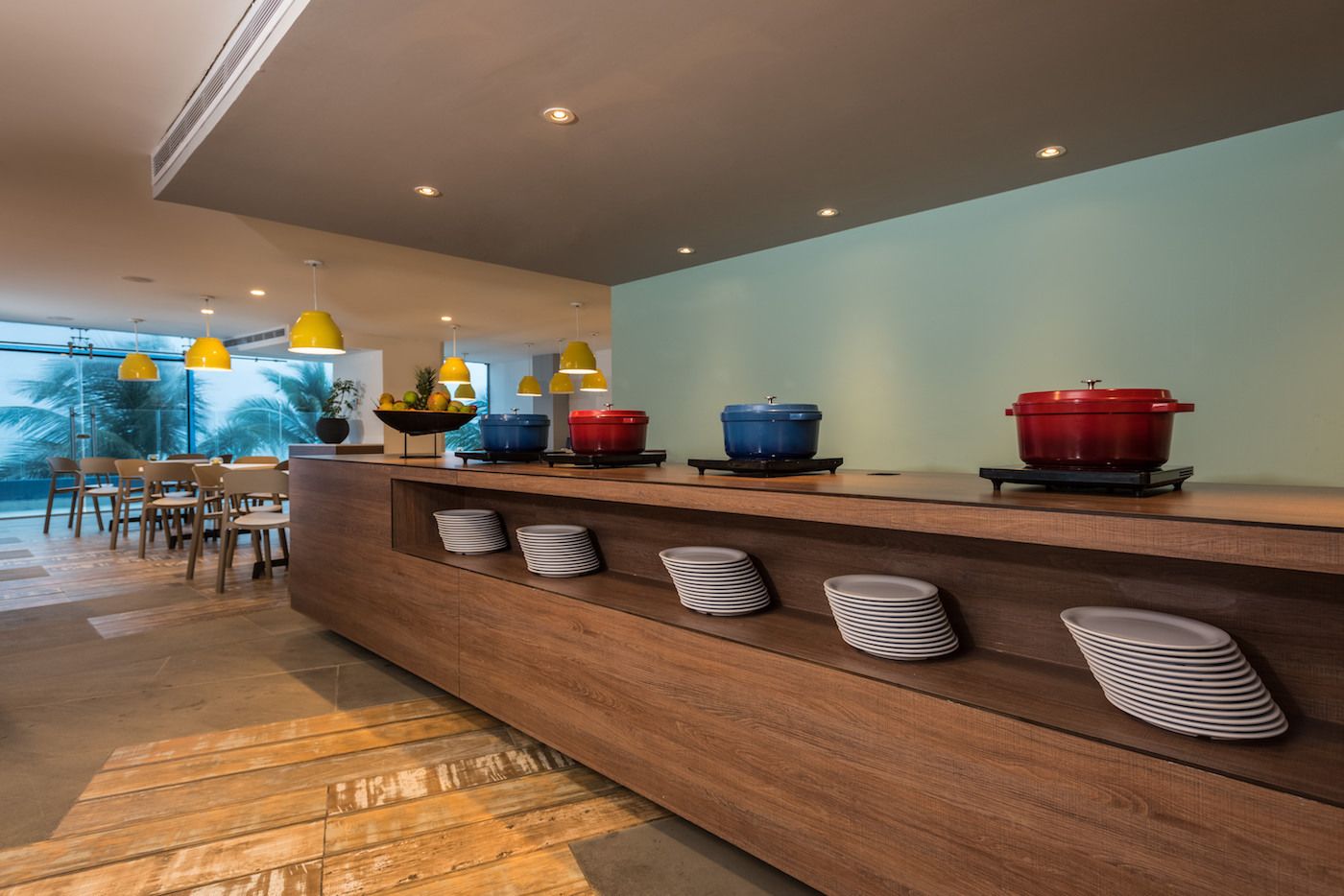 A modern kitchen with a wooden countertop, colorful pots, and a dining area with chairs and a table.