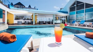 Ein Poolbereich mit Liegestühlen, einer Bar und einem Getränk.
