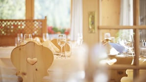 A dining table set with wine glasses and a wooden chair with a heart cutout. - Hotel Casanna (Davos)