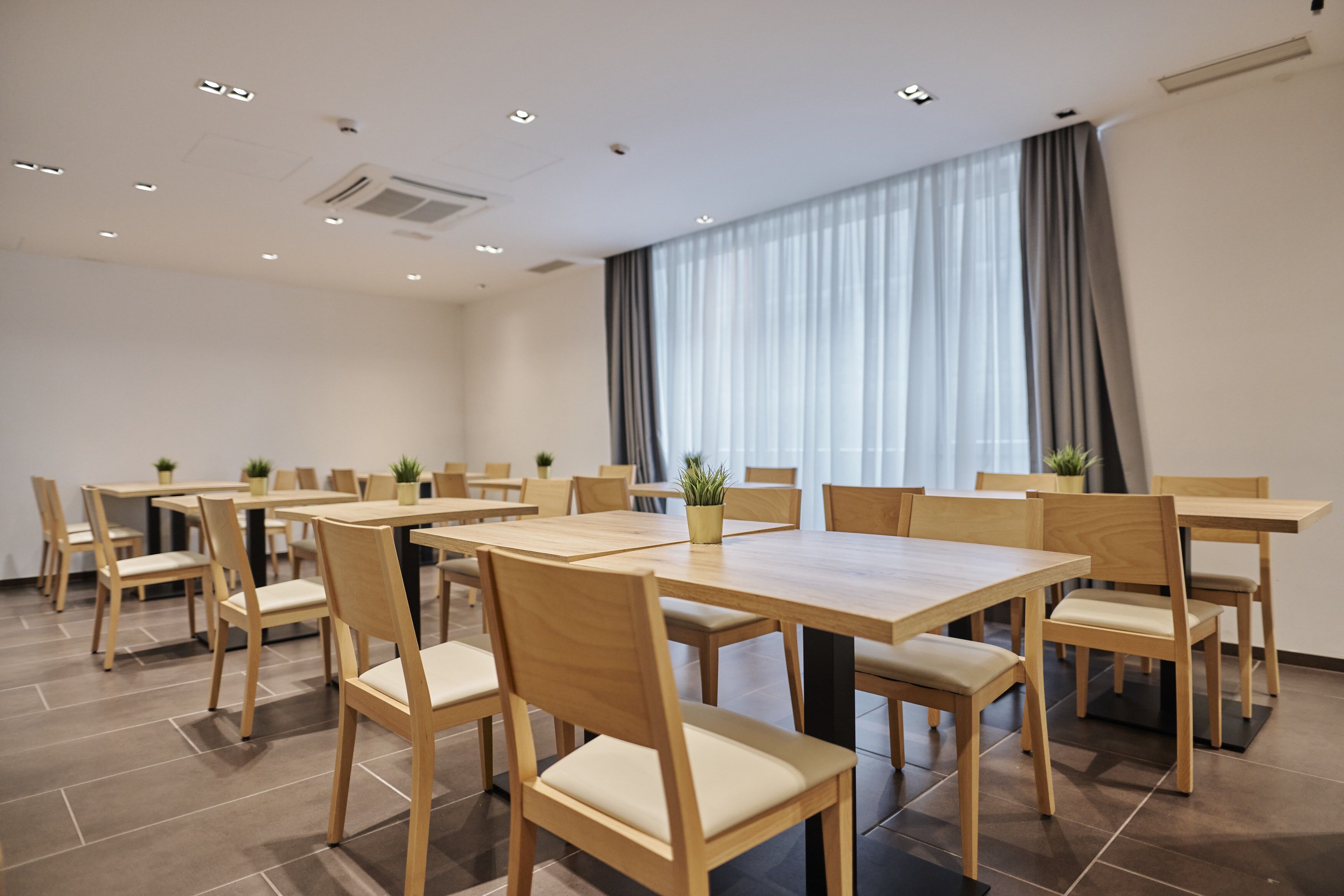 Een congreszaal met meerdere houten tafels en stoelen, gerangschikt in een U-vorm.