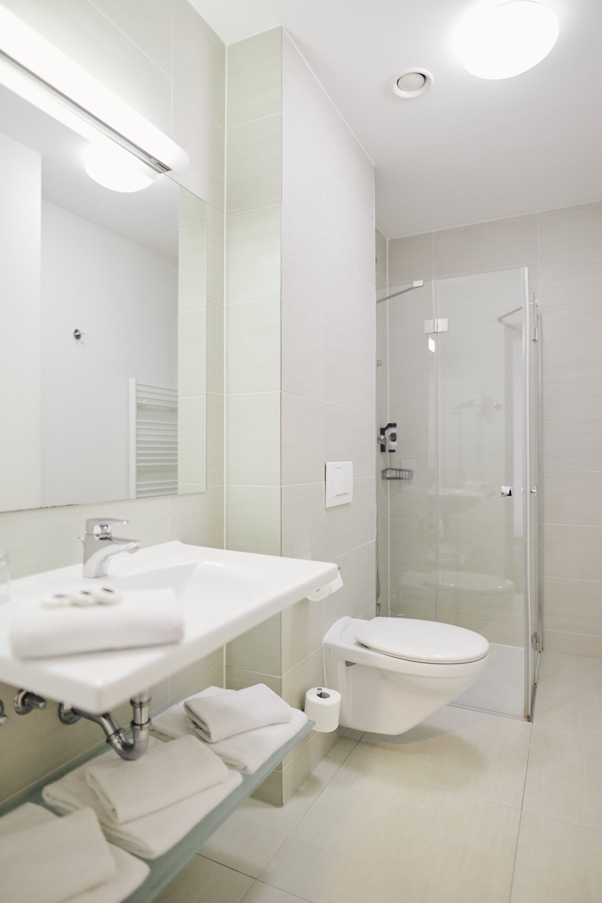 A modern bathroom with a white sink, mirror, and toilet.