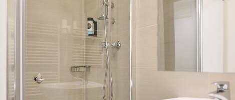 A modern bathroom with a glass-enclosed shower, a white sink, and a mirror above the sink.
