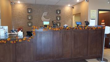 A reception desk with a wooden counter, framed pictures, a crescent moon decoration, and autumn leaves.