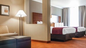 A hotel room with a bed, a desk, a chair, a lamp, and a large mirror. - Comfort Suites Farmington (Farmington)