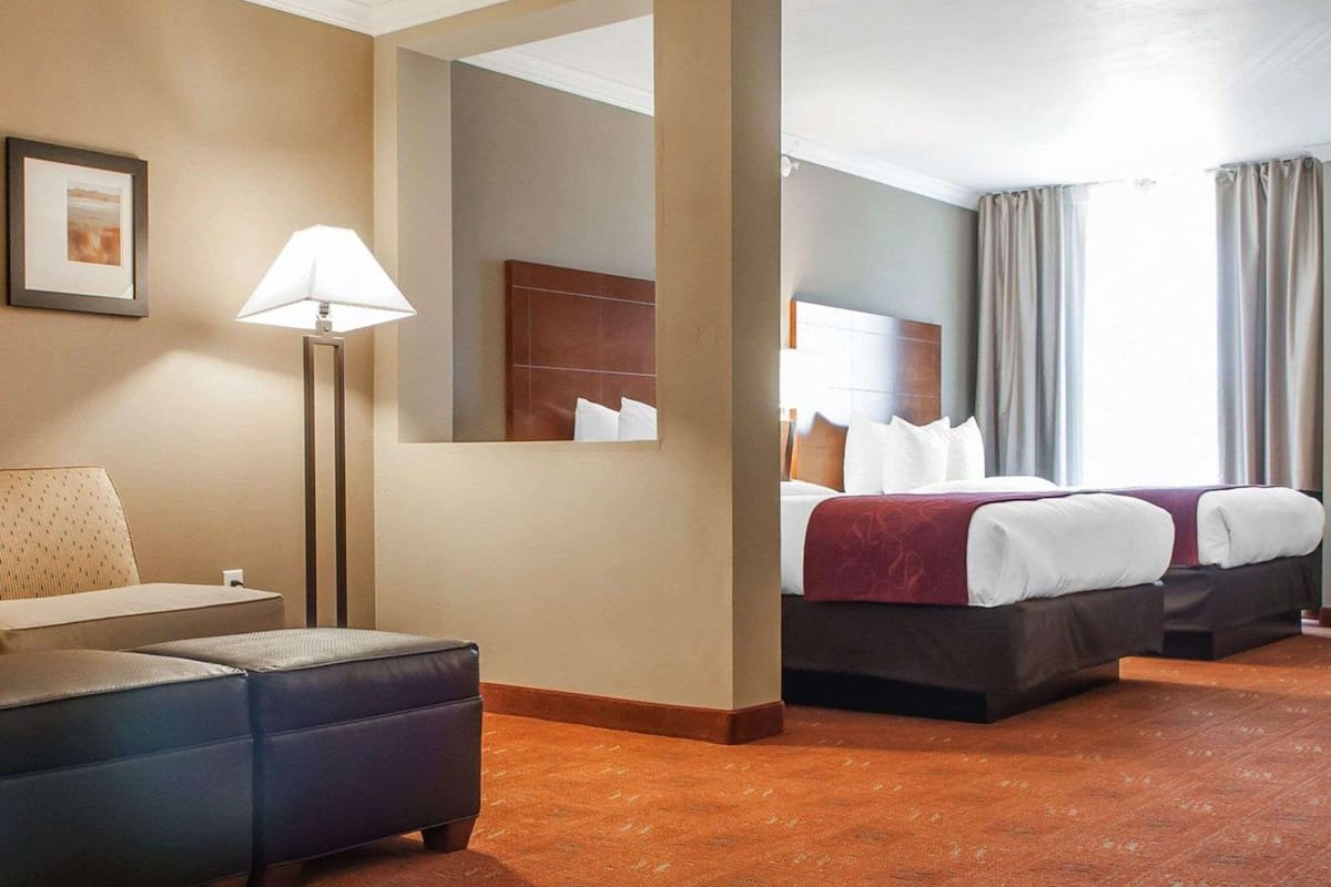 Ein Hotelzimmer mit Bett, Schreibtisch, Stuhl, Lampe und einem großen Spiegel.