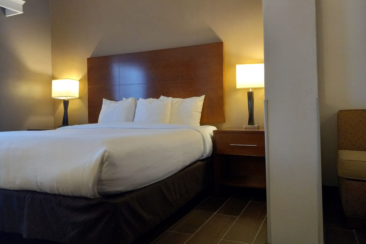 Ein Hotelzimmer mit einem großen Bett, zwei Nachttischen und einem Sessel.