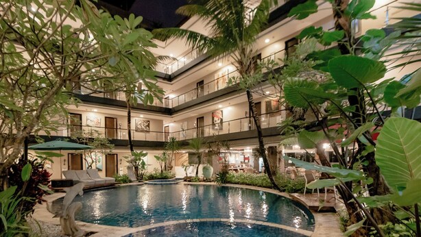 A multi-level hotel with a swimming pool surrounded by lush greenery.