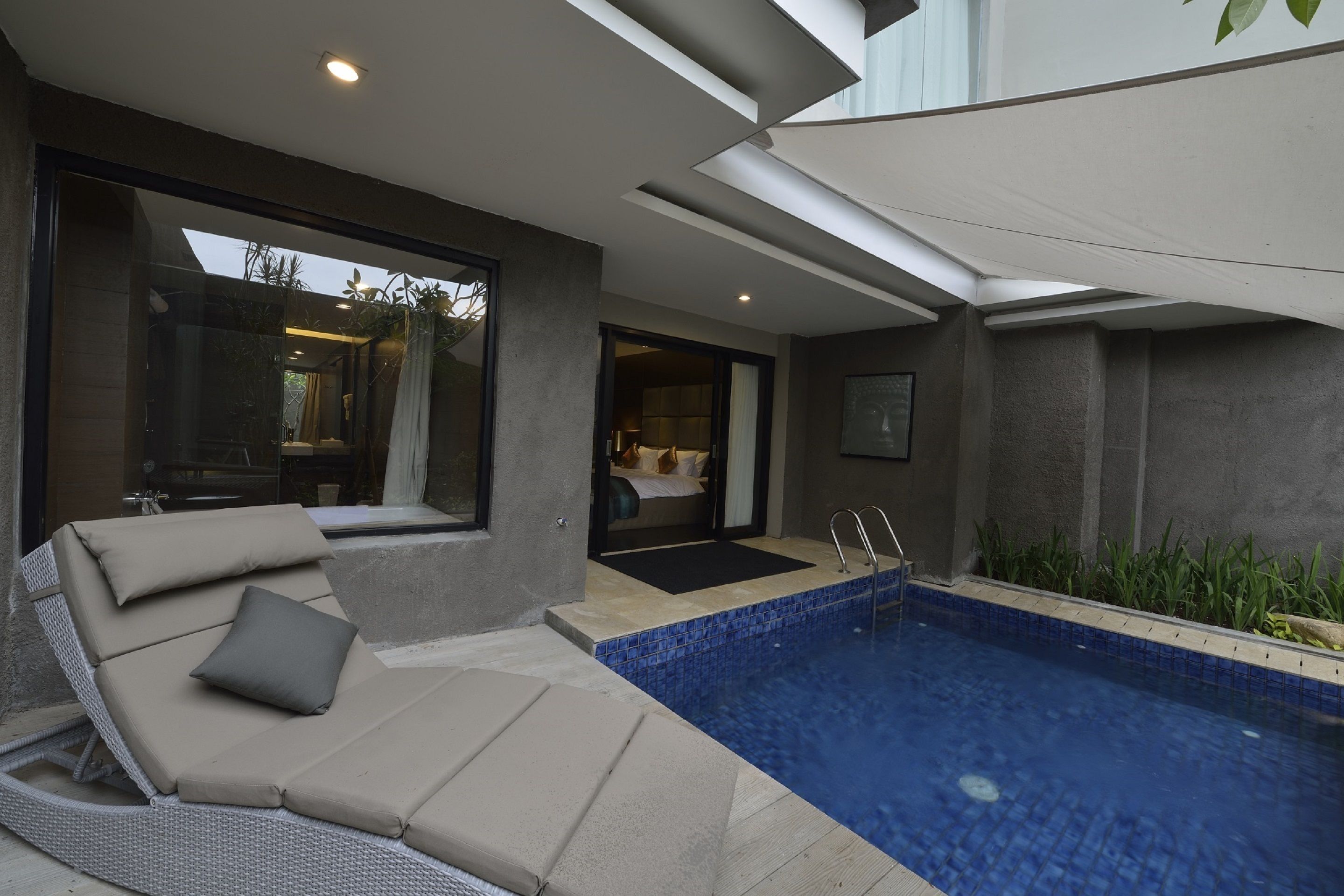 Ein moderner Poolbereich im Freien mit einer Liege und einer Glastür zum Schlafzimmer.