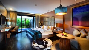 A modern hotel room with a large bed, a desk, a sofa, a round coffee table, and a view of a swimming pool.