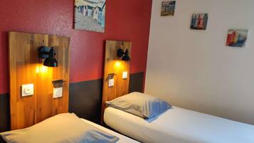 Une chambre d’hôtel avec deux lits, des têtes de lit en bois, des lampes fixées au mur et un mur d’accent de couleur rouge.