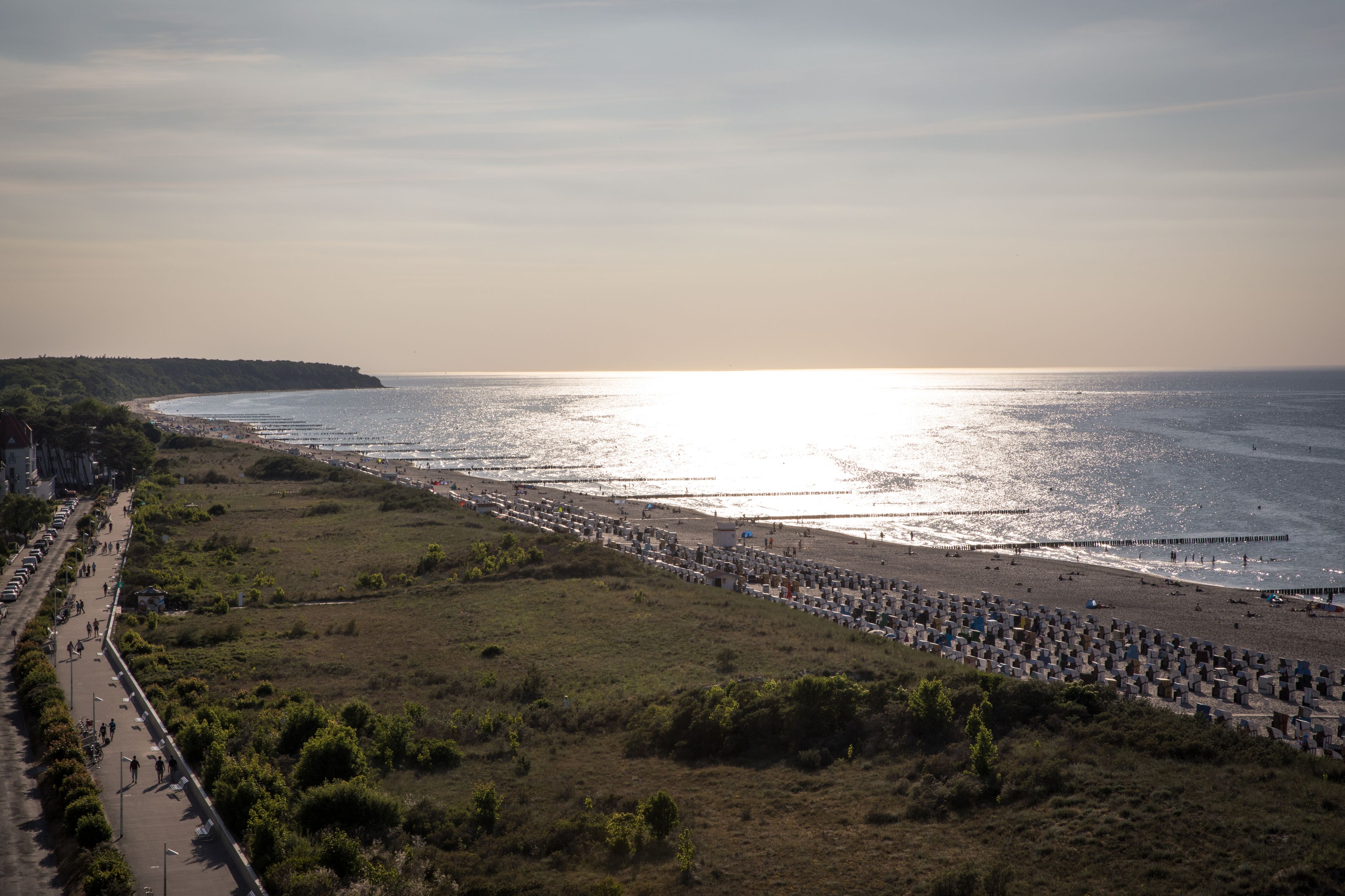 A coastal view with a beach, a promenade, and a pier extending into the sea.