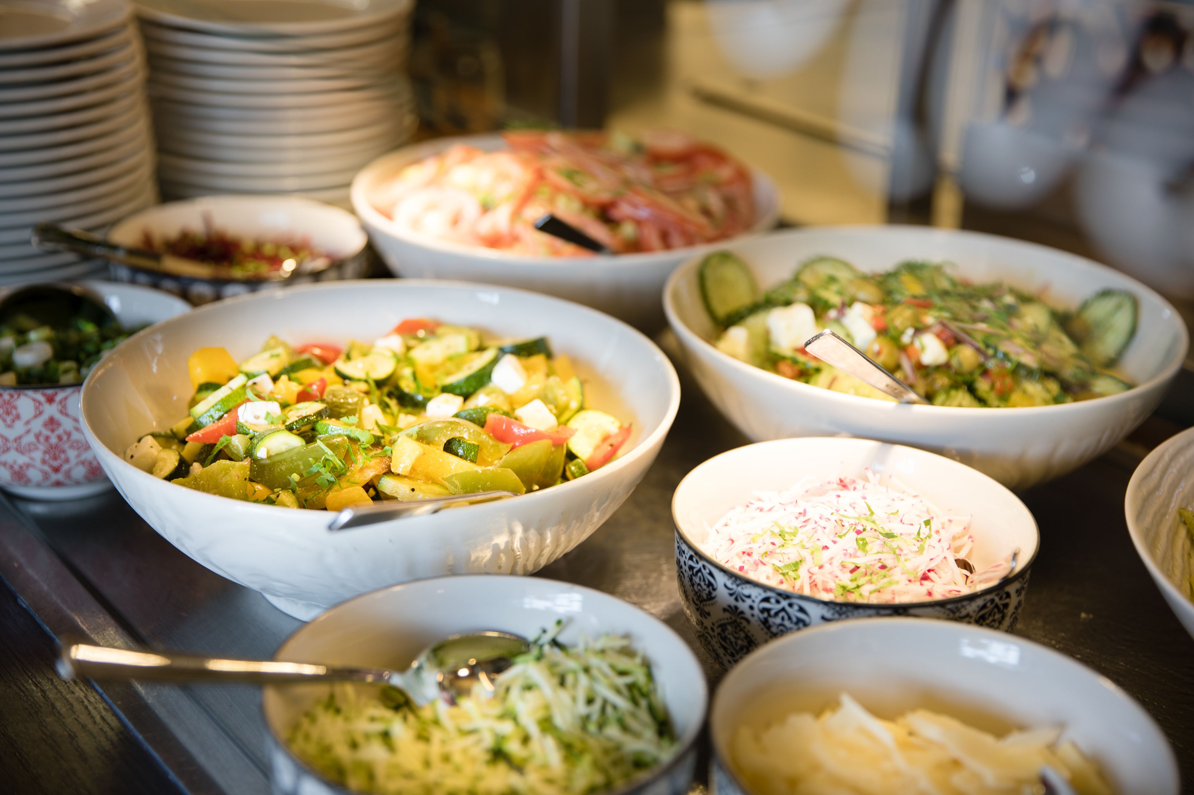 A buffet with various dishes including salads, vegetables, and a pasta dish.
