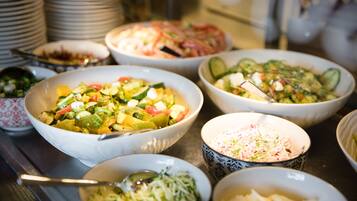 Ein reichhaltiges Buffet mit verschiedenen Speisen, darunter Salate, Gemüse und ein Nudelgericht.