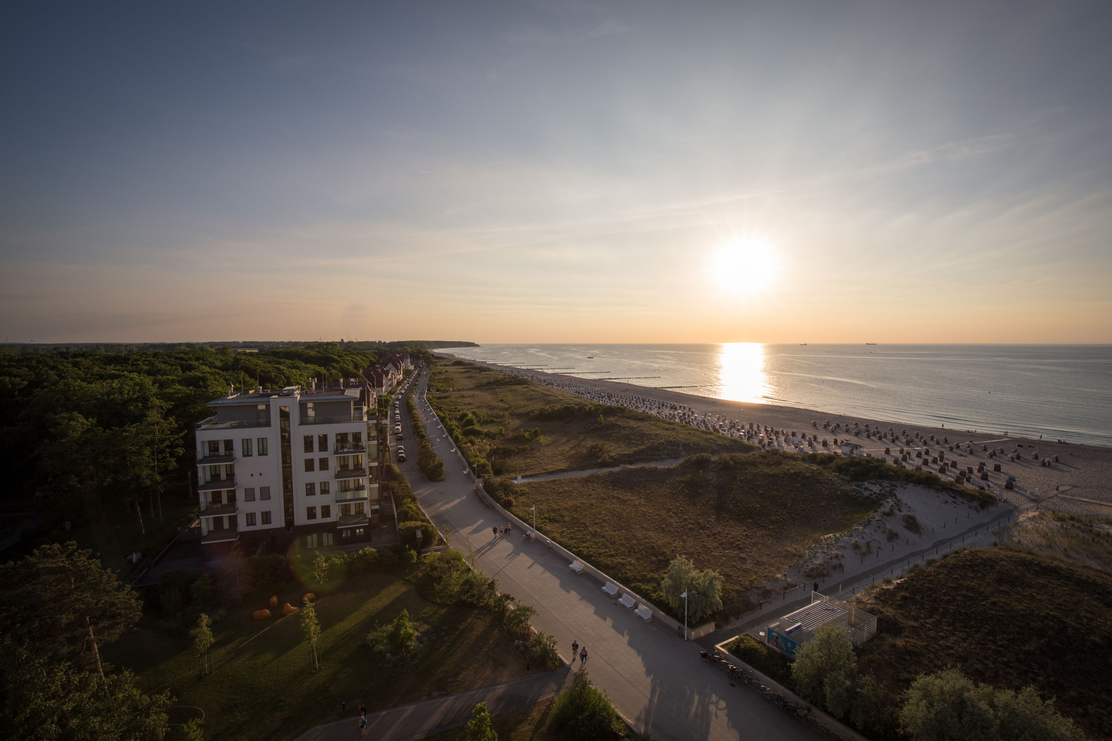 Una vista aerea di una zona costiera con spiaggia, strada e complesso di edifici.