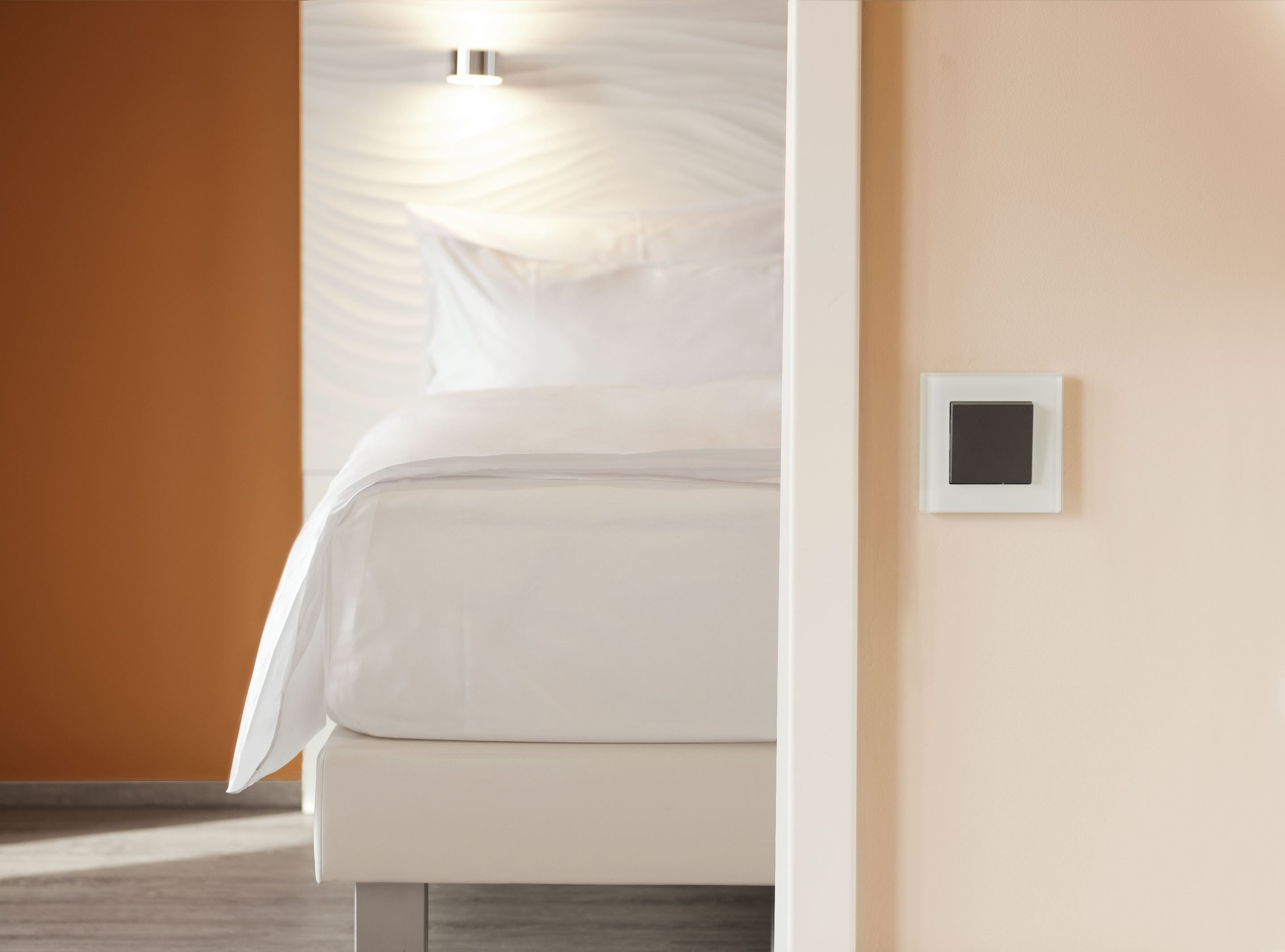 Un dormitorio con una cama, una luz empotrada en la pared y un termostato.