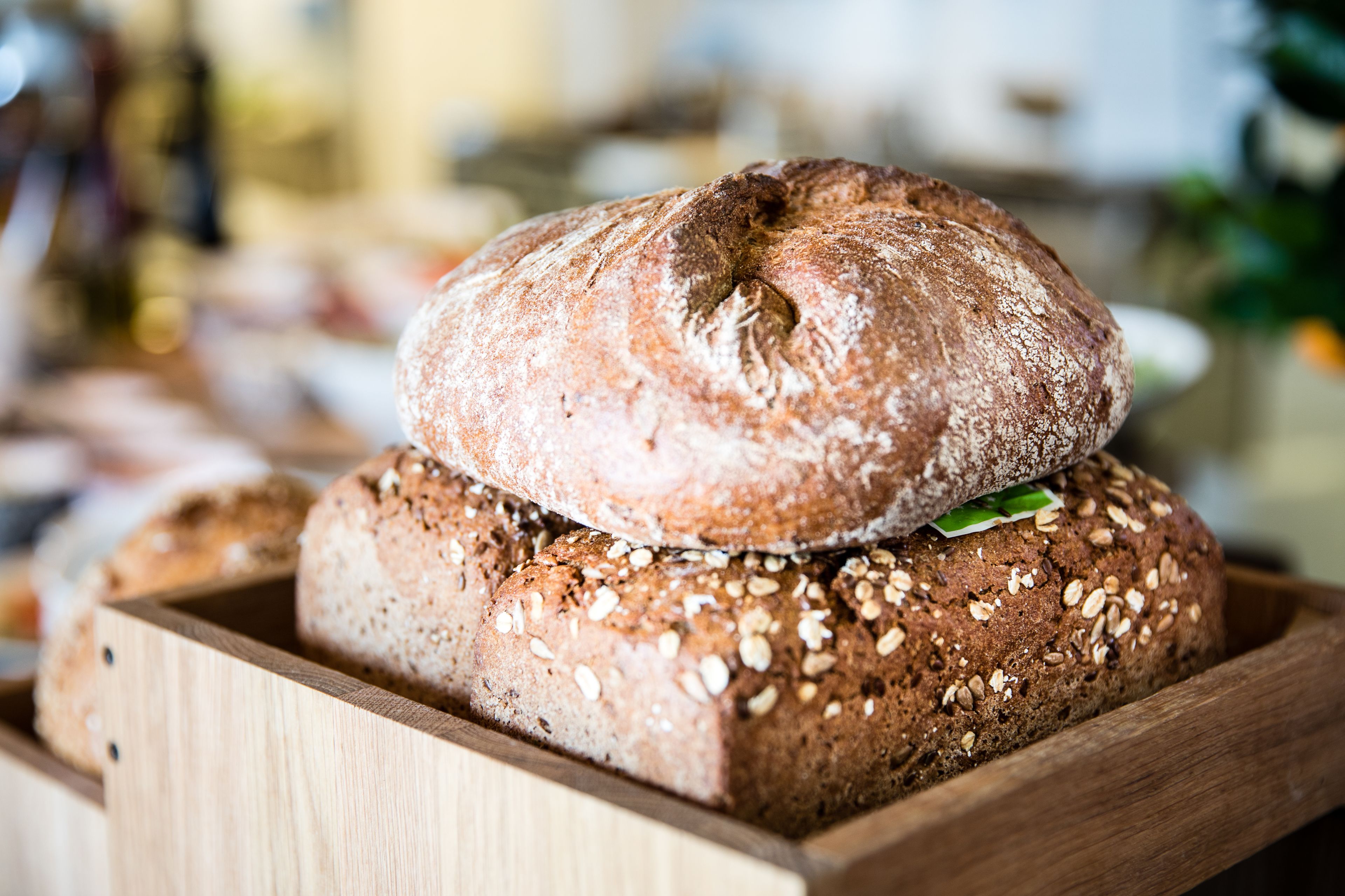 Eine Holzkiste mit verschiedenen Brotsorten, darunter ein Brot mit Saaten.