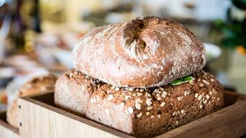 Eine Holzkiste mit verschiedenen Brotsorten, darunter ein Brot mit Saaten.
