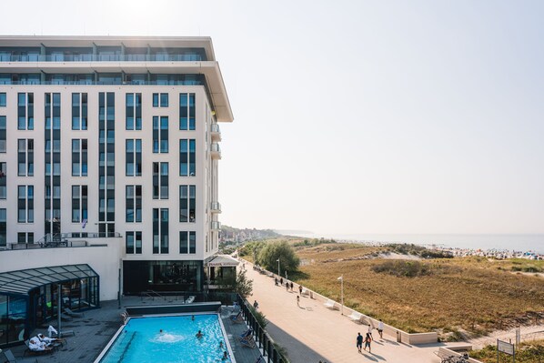 A modern hotel with a swimming pool, a beach view, and a restaurant.