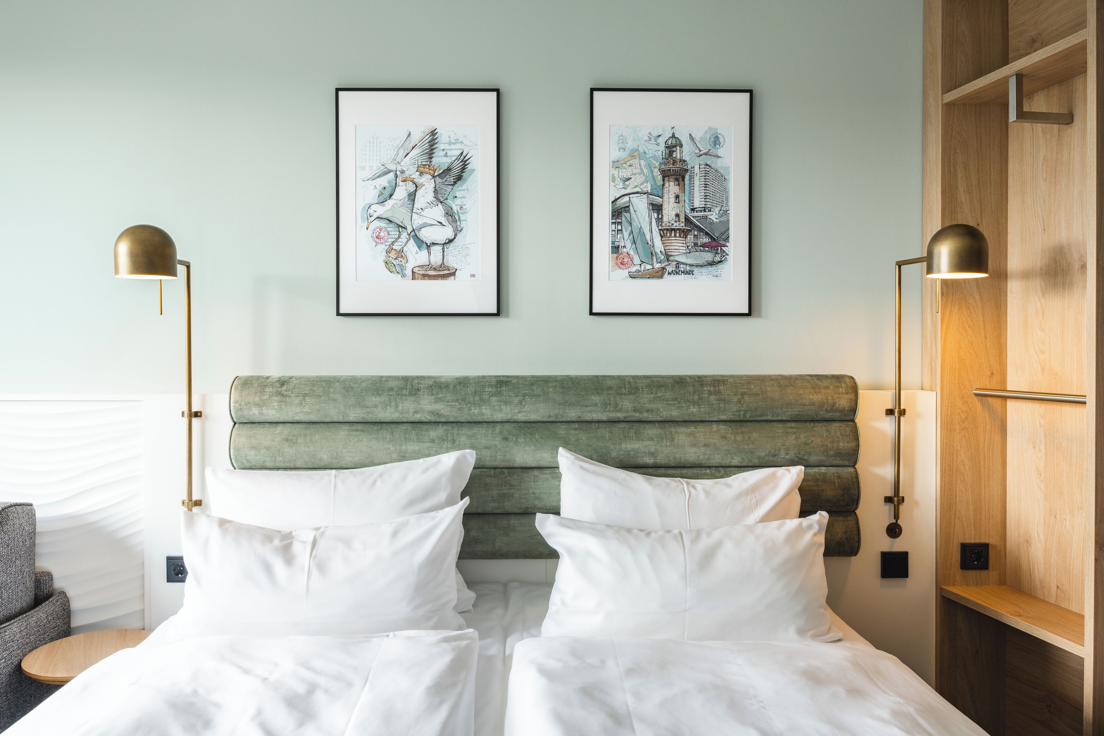 Ein Hotelzimmer mit einem Bett, zwei gerahmten Kunstwerken an der Wand und zwei Stehlampen.