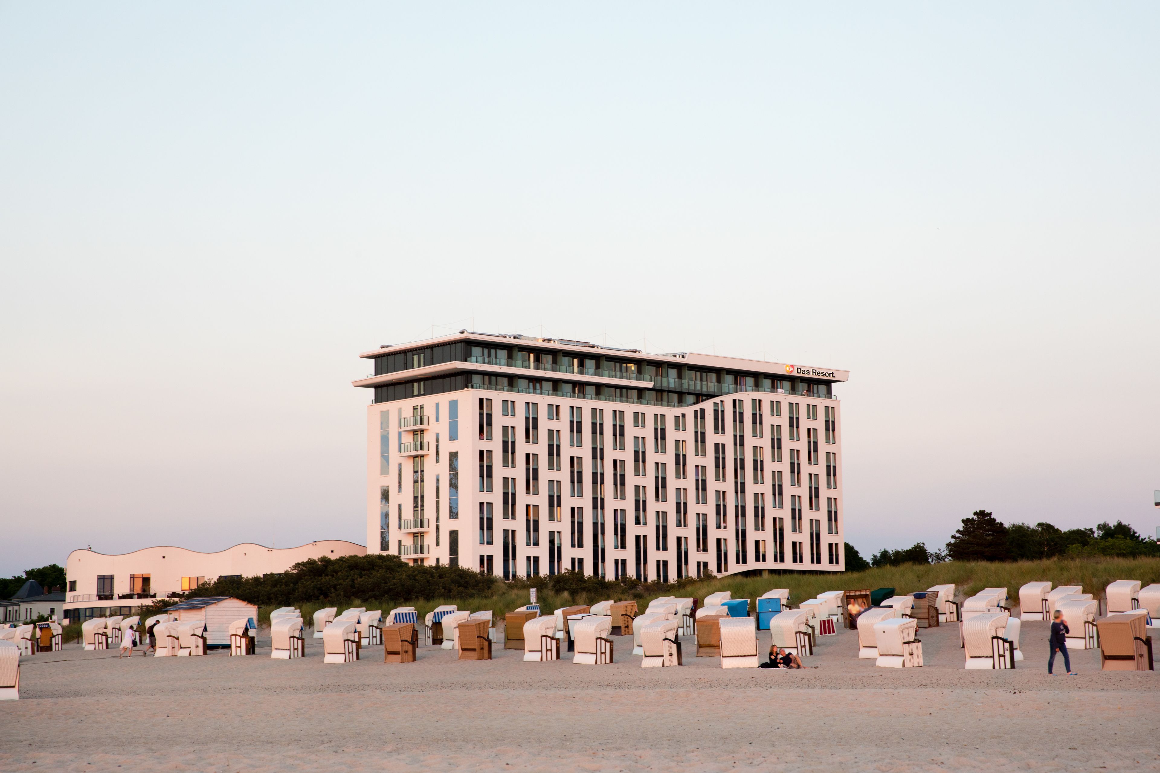 A modern building with a flat roof and a sign reading "Das Resort."