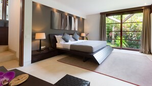 A modern hotel room with a large bed, a desk with a laptop, and a view of greenery through the window. - The Layar Designer Villas and Spa (Seminyak)